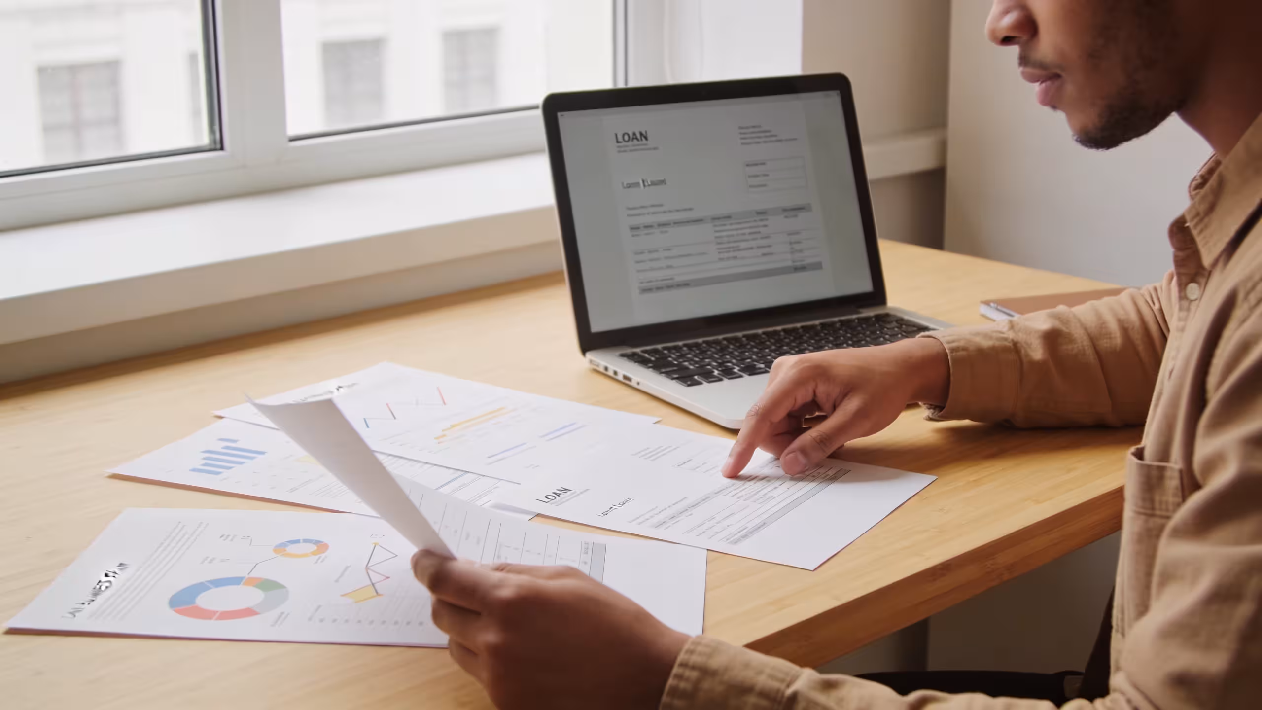Startup business owner reviewing loan options at a desk with documents and a laptop
