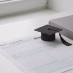Best student loans for bad credit: financial aid paperwork and a graduation cap on a white desk
