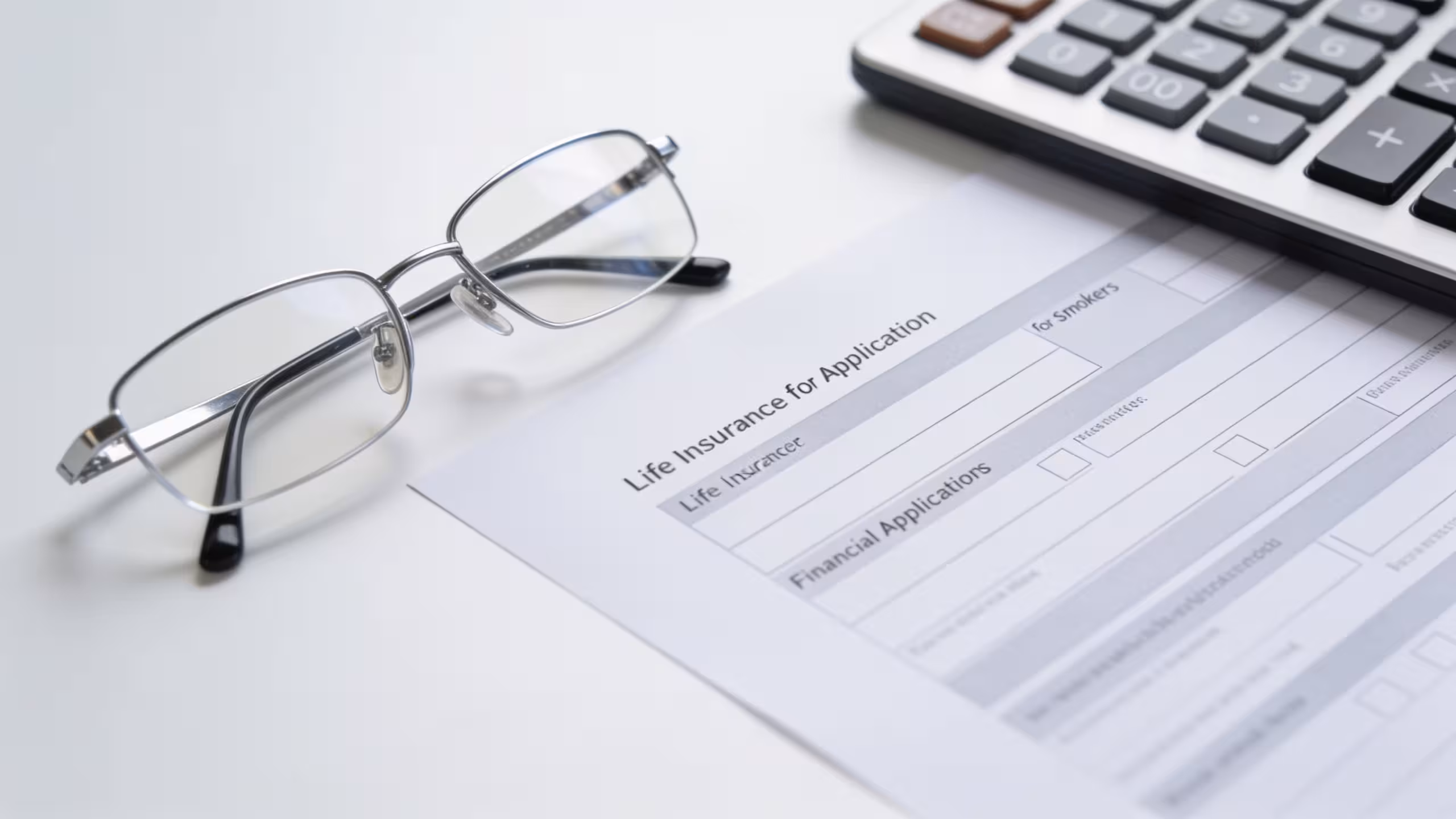 Life insurance policy document and pen on a wooden desk, illustrating life insurance for smokers rate options.